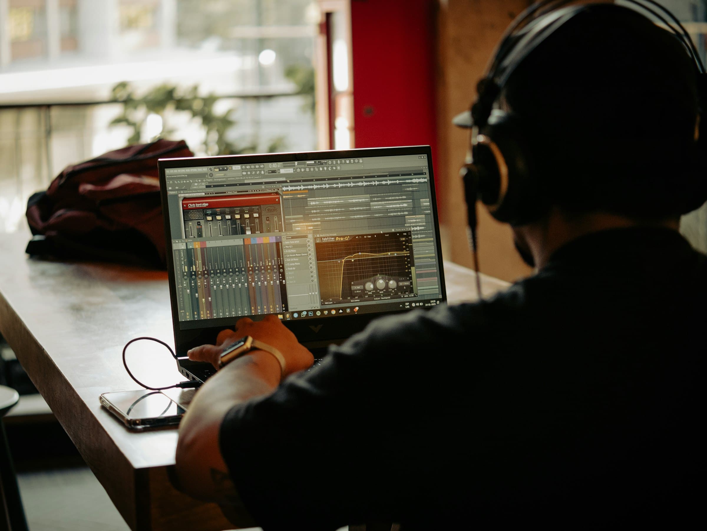 A person wearing headphones editing audio on a laptop