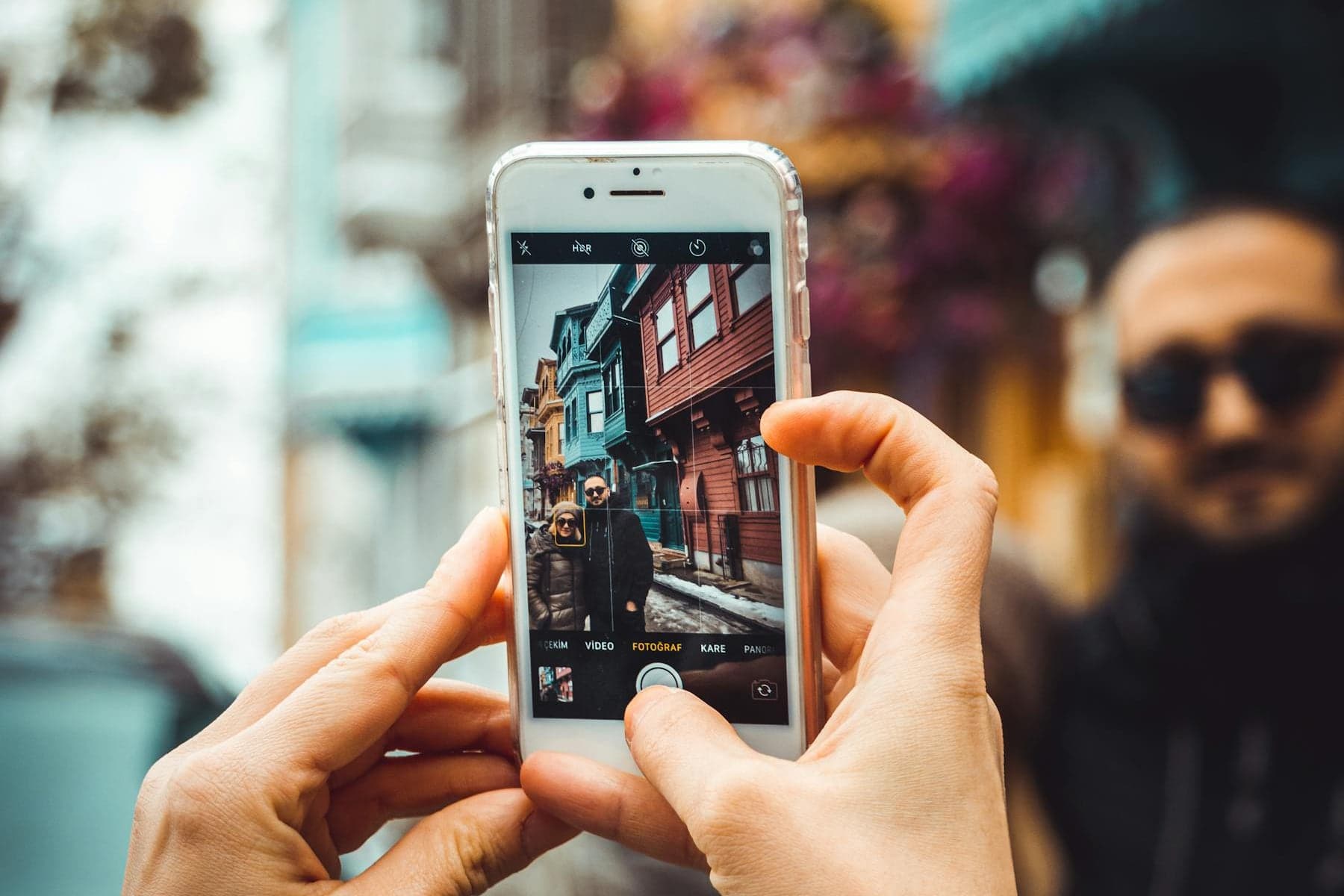 A person taking a phone photo in a city street