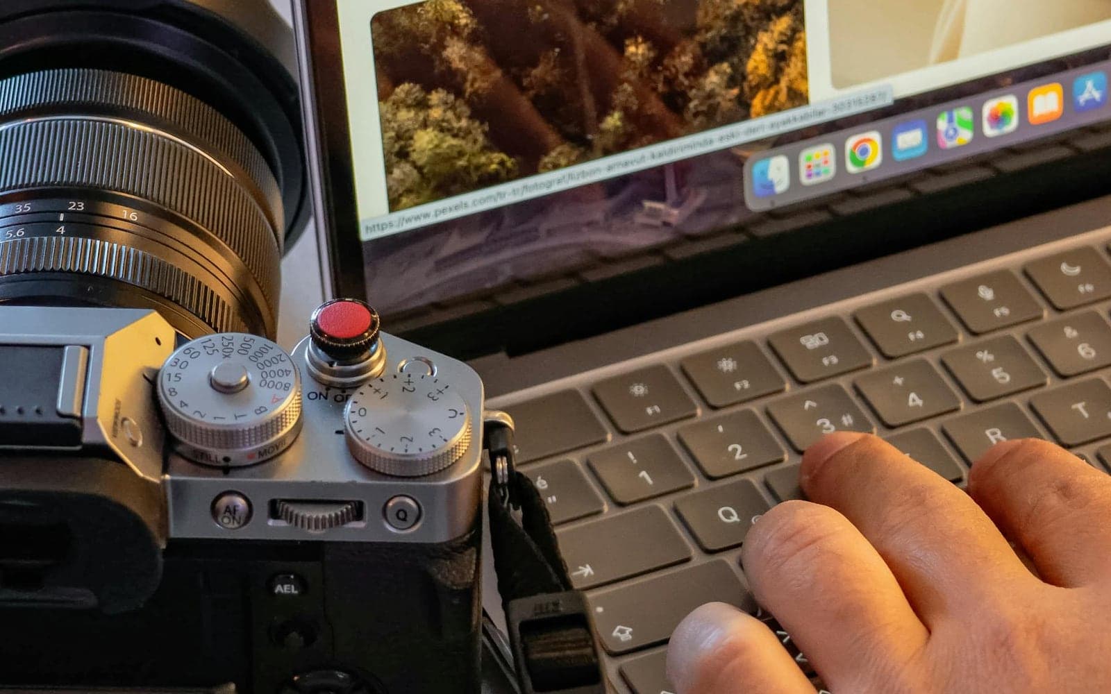 A camera beside a laptop used for photo editing